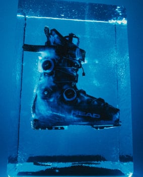 Ein schwarzer Head-Skischuh ist in einem blauen Eisblock eingefroren.