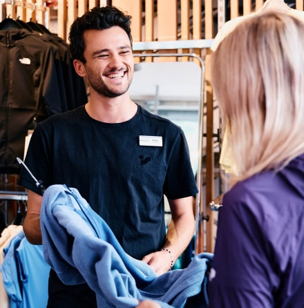 INTERSPORT Mitarbeiter führt gerade ein Beratungsgespräch und lacht dabei.