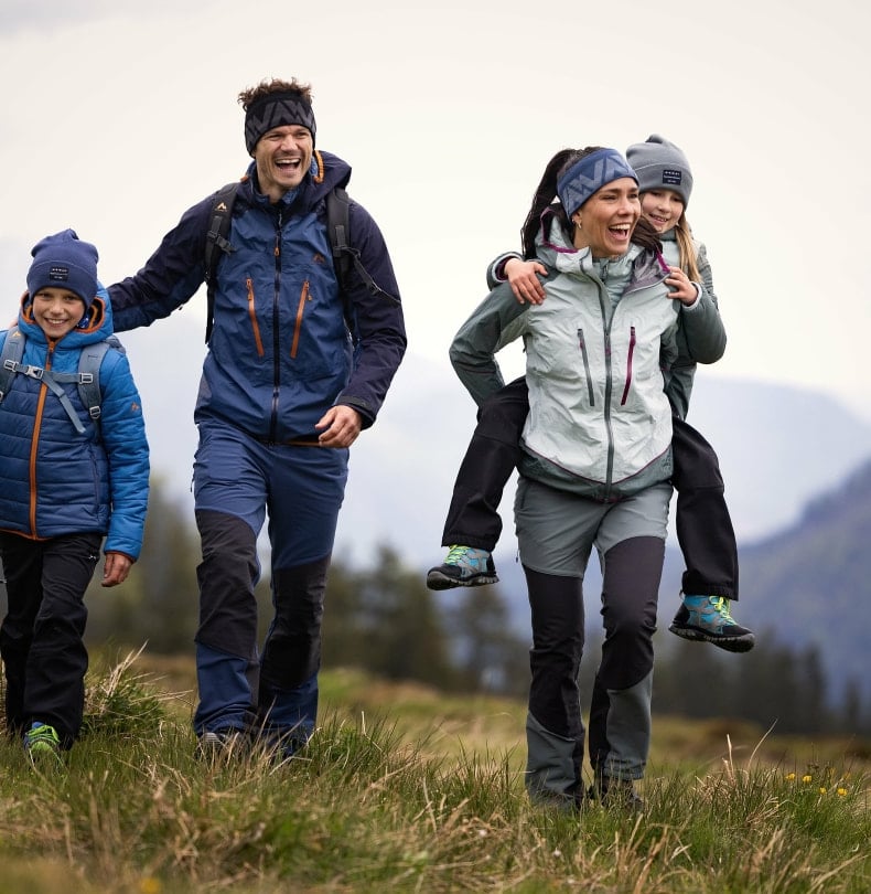 Eine glückliche Familie wandert lachend zusammen in den Bergen.