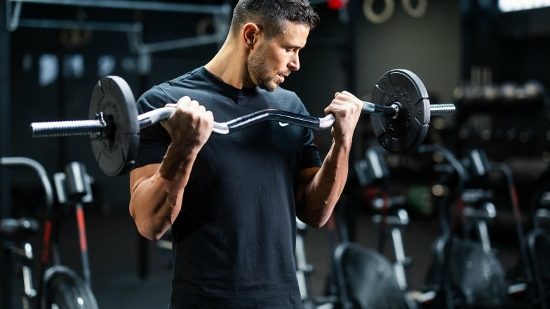 Ein Mann trainiert in einem Fitnessstudio mit einer SZ-Hantel.
