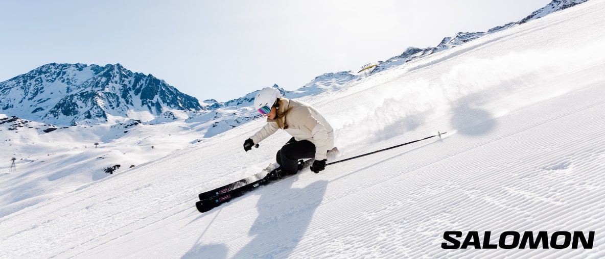 Eine Skifahrerin fährt eine Piste in den verschneiten Bergen hinunter.