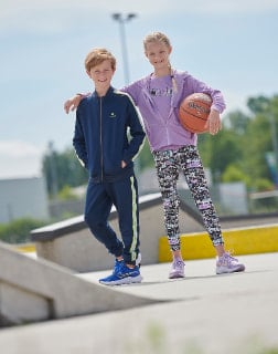 Dívka a chlapec stojí na hřišti s basketbalovým míčem.