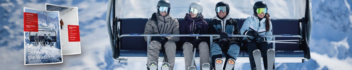 Vier lachende Skifahrer auf einem Sessellift in den verschneiten Bergen.