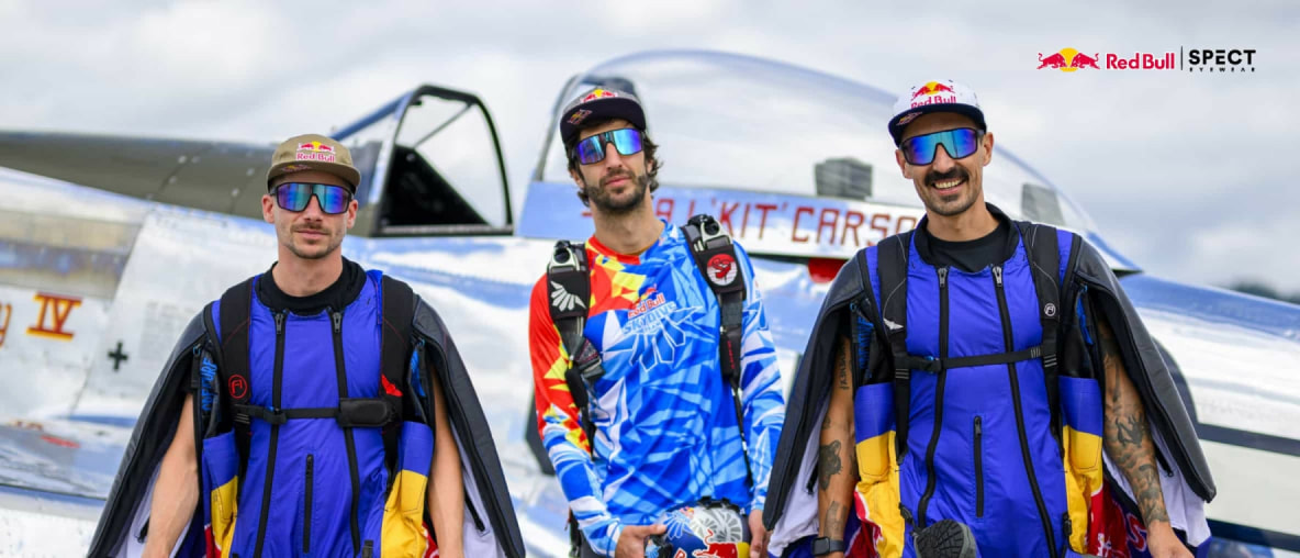 Tři členové Red Bull skydiving teamu pózují před letadlem v leteckých kombinézách a brýlích Red Bull SPECT.