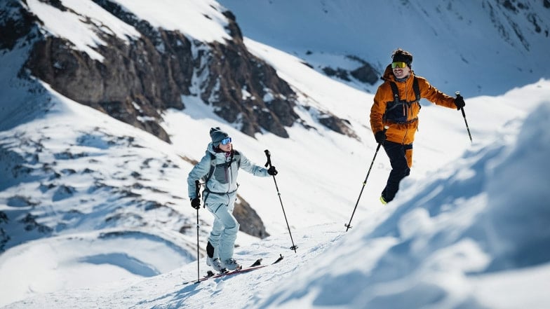 Zwei Personen auf Skitour in einer verschneiten Berglandschaft im Winter.