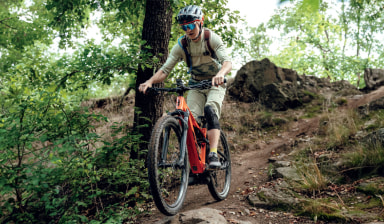 Jezdkyně na elektrokole KTM Macina Chacana 792 projíždí lesní trail v lehkém terénu.