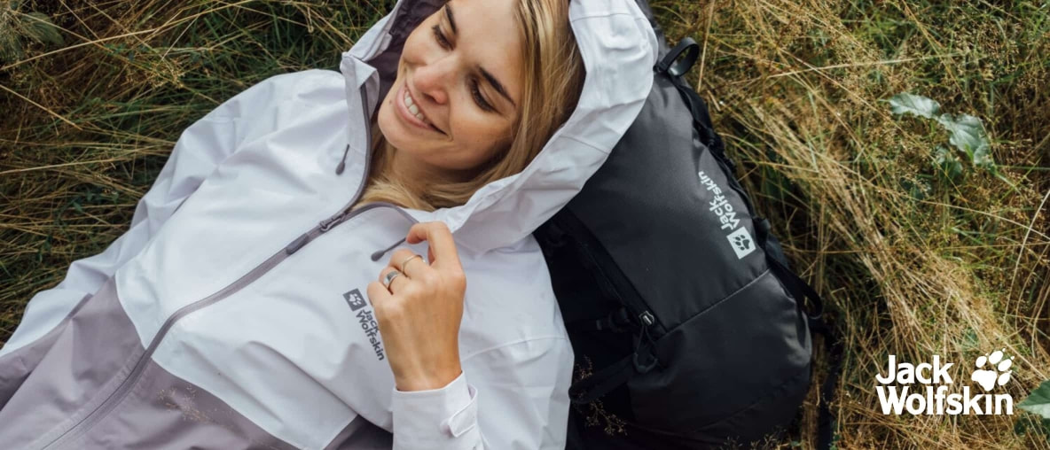 Sorgenfrei und frei – eine Wanderin genießt die Natur, trocken verpackt in Jack Wolfskin, mitten auf der feuchten Wiese.