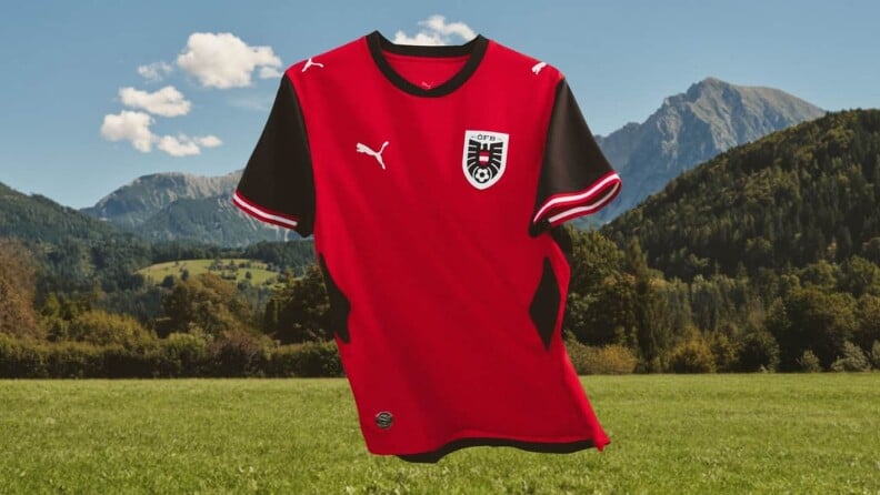 Rotes Fußballtrikot der österreichischen Nationalmannschaft freigestellt vor Berg- und Wiesenlandschaft.