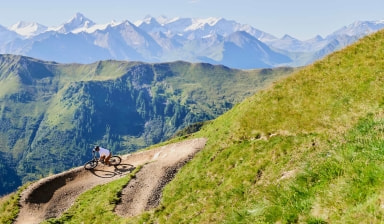 Auf dem Trail nach unten mit wunderschönem Bergpanorama im Hintergrund.