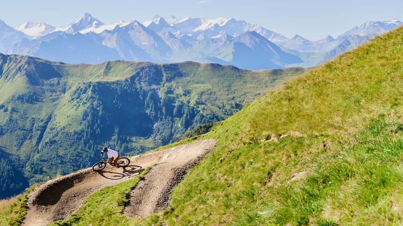 Auf dem Trail nach unten mit wunderschönem Bergpanorama im Hintergrund.