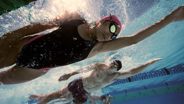 Eine Schwimmerin und ein Schwimmer ziehen ihre Bahnen im Kraulstil.