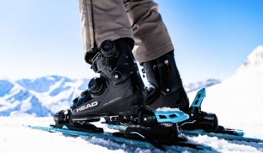 Nahaufnahme von Head Skischuhen und Skiern im Schnee der Berge.