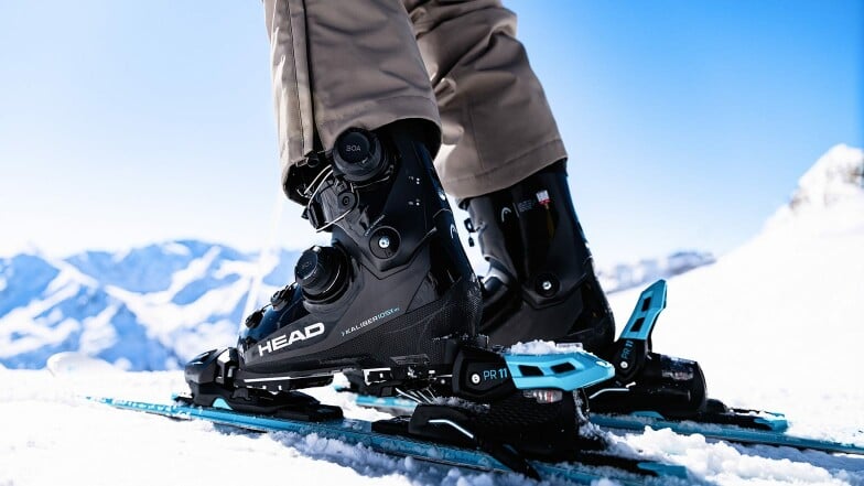 Nahaufnahme von Head Skischuhen und Skiern im Schnee der Berge.