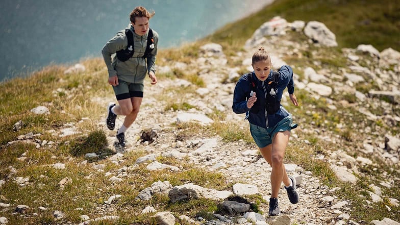 Ein Mann und eine Frau beim Trailrunning in den Bergen. Ihre Getränke transportieren sie in einer Trailrunning-Weste.