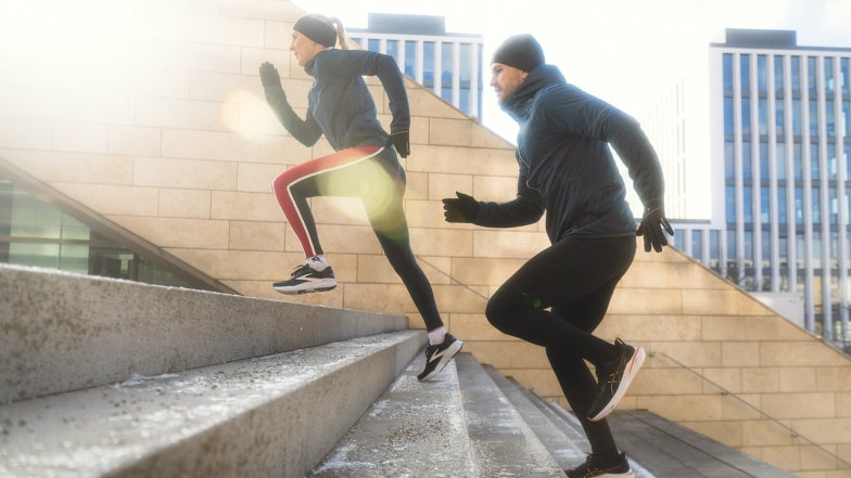 Zwei Personen laufen im Winter eine Treppe in der Stadt hoch.