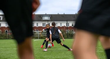 Zwei jugendliche Fußballspielerinnen kämpfen auf einem Fußballplatz in der Stadt um den Ball.