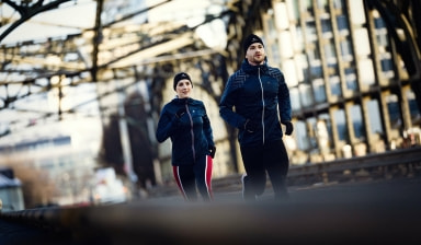 Ein Mann und eine Frau joggen bei kaltem Wetter.