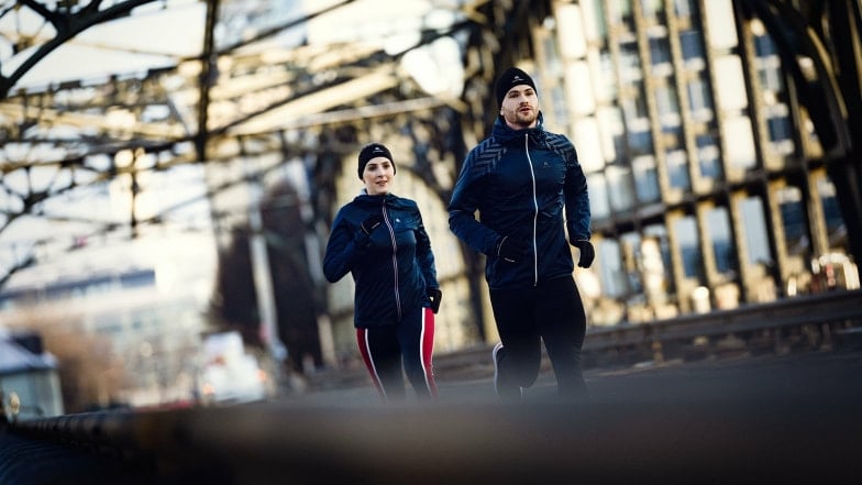 Ein Mann und eine Frau joggen bei kaltem Wetter.
