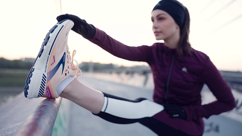 Läuferin beim Dehnen. Die Laufschuhe von Brooks werden sie viele Kilometer weit tragen.