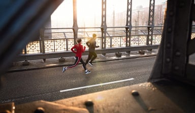 Ein Paar joggt bei Sonnenaufgang über eine Brücke in der Stadt im Winter