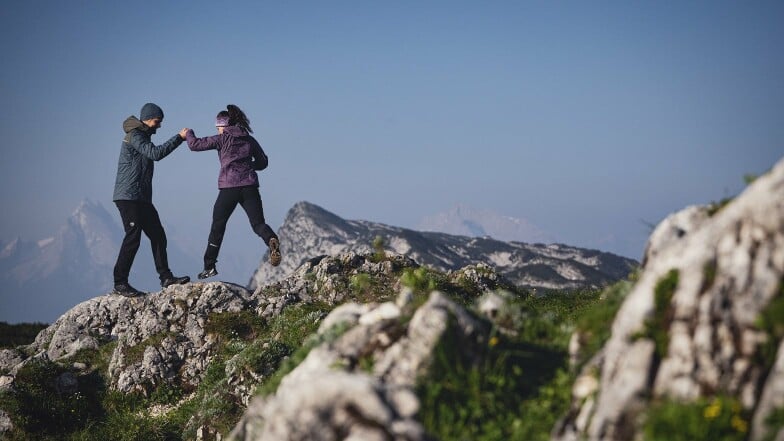 Ein Mann und eine Frau wandern auf einem steinigen Bergpfad – hier ist eine gute Balance nötig.