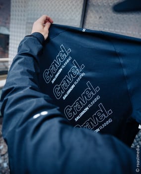 Ein dunkelblaues Shirt mit dem Aufdruck Gravel Through Austria wird hochgehalten.
