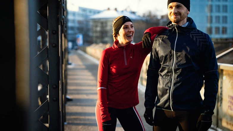 Ein sportliches Paar macht eine Pause beim Laufen auf einer Brücke.