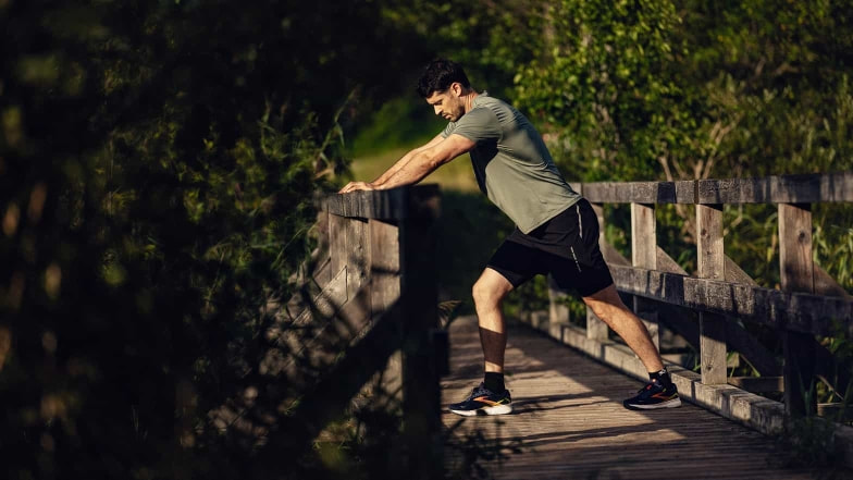 Dieser Läufer dehnt seine Beinrückseite nach dem Lauf als teil seines regenerierenden Cool Downs.