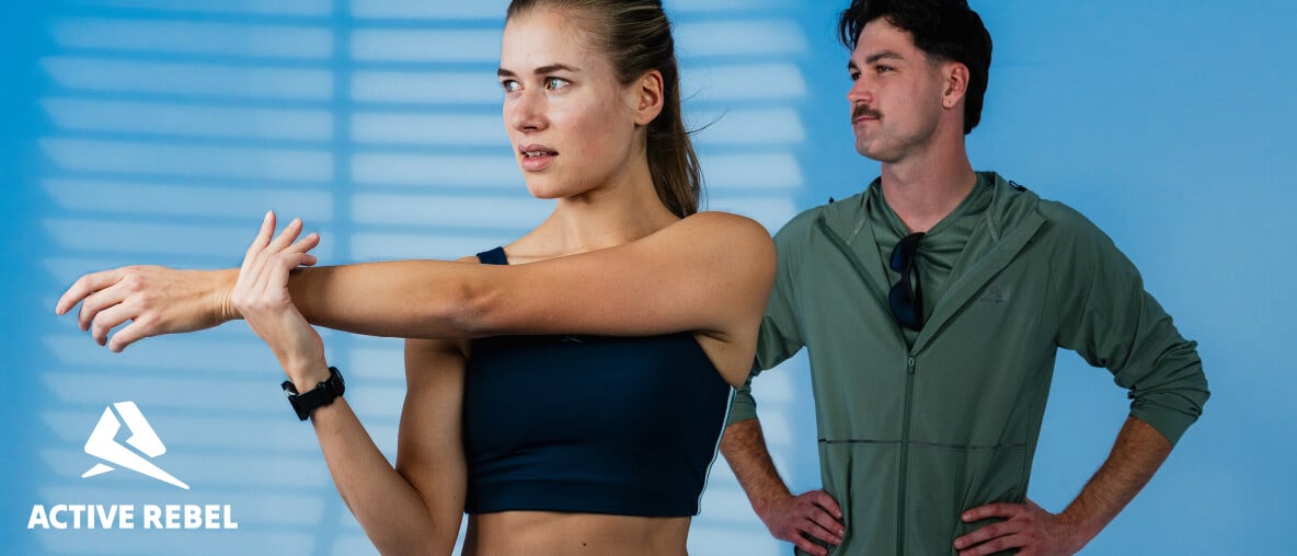 Zwei Personen führen Dehnübungen in einem Studio vor blauem Hintergrund aus. Ein Logo ist links im Bild sichtbar.