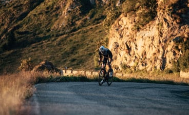 Rennradfahrer auf einer Bergstraße mit MET Fahrradhelm in weiß