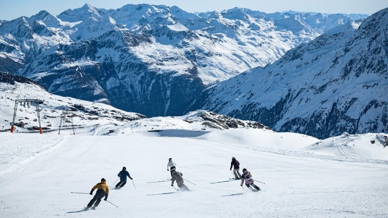 Eine Gruppe von Skifahrern auf einer Piste in den Alpen.