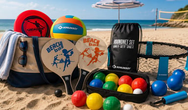 Badetasche mit Beachvolleyball, Roundnet-Set, Beachball-Schlägern, Frisbee und Boccia-Kugeln am Strand – Sportequipment für einen aktiven Sommertag.