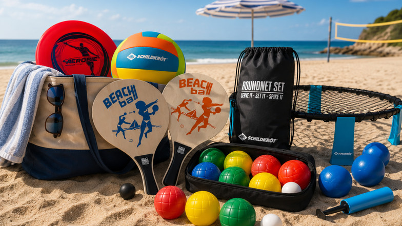 Badetasche mit Beachvolleyball, Roundnet-Set, Beachball-Schlägern, Frisbee und Boccia-Kugeln am Strand – Sportequipment für einen aktiven Sommertag.