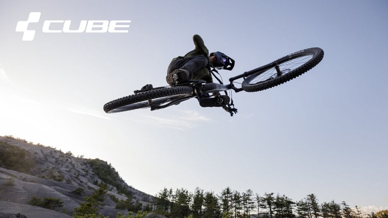 Ein Mountainbiker führt einen waghalsigen Sprung auf einer MTB Strecke aus.