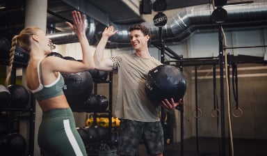 High five zwischen einer Frau und einem Mann im Fitnessstudio nach dem erfolgreichen Training.