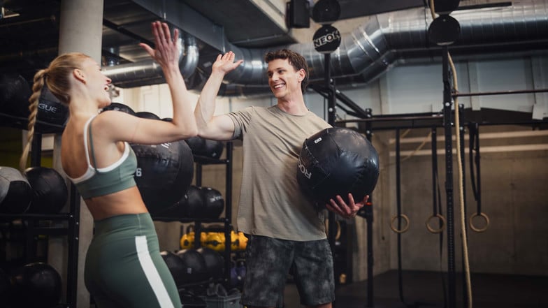 High five zwischen einer Frau und einem Mann im Fitnessstudio nach dem erfolgreichen Training.