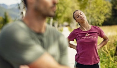 Eine Läuferin dehnt ihren Nacken  nach einem gemütlichem Regenerationslauf. Ihr Laufpartner dehnt seine Schulterpartie.
