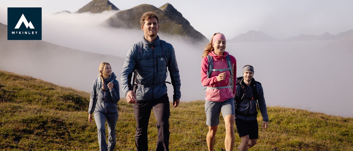 Vier junge Leute wandern in den Bergen über den Wolken.