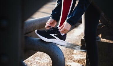 Eine Person bindet sich die Schnürsenkel an einem Laufschuh zu.