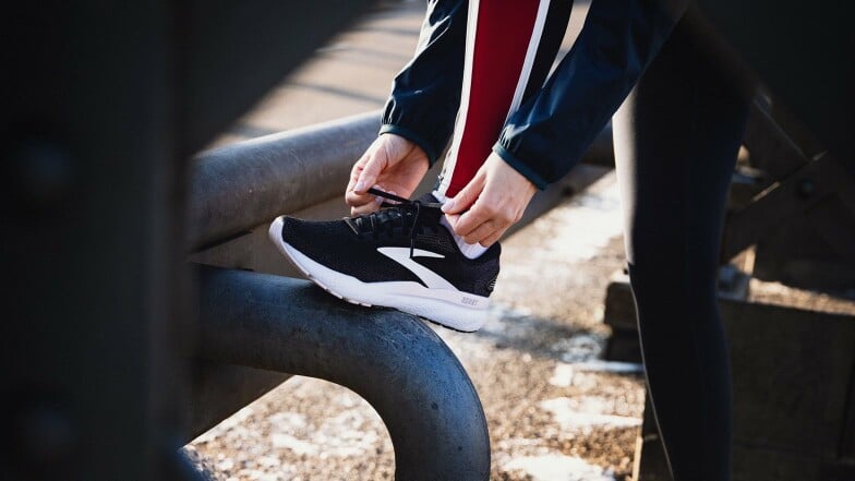 Eine Person bindet sich die Schnürsenkel an einem Laufschuh zu.