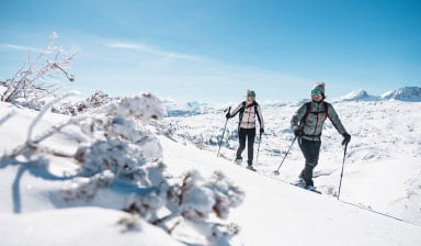 Ein Paar auf einer Skitour in einer sonnigen Berglandschaft.