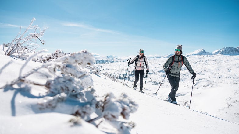Ein Paar auf einer Skitour in einer sonnigen Berglandschaft.