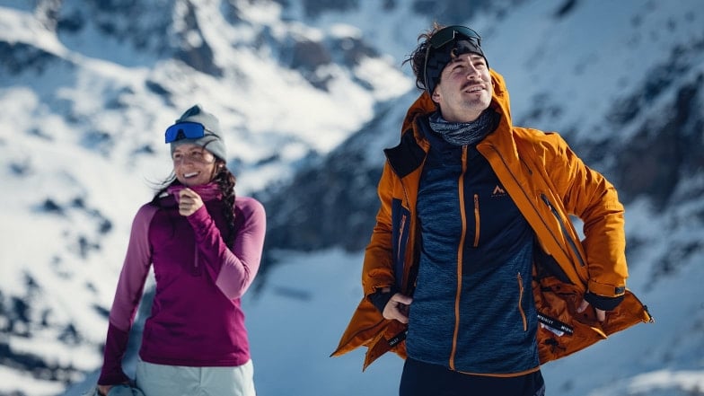 Ein Paar in Winterkleidung in einer verschneiten Berglandschaft.