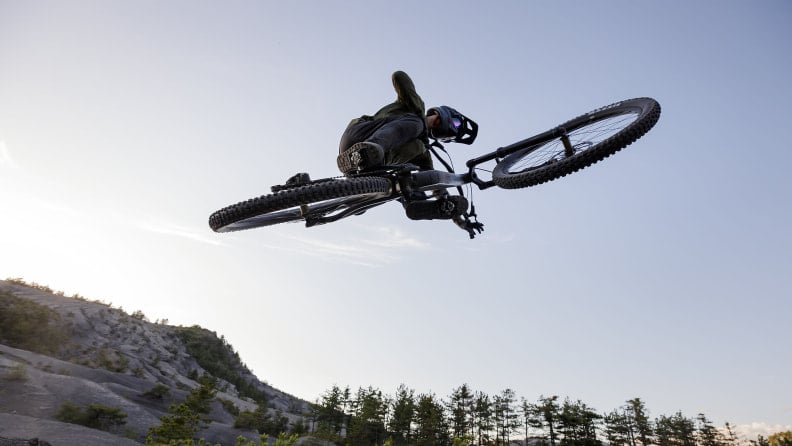 Ein Mountainbiker führt einen waghalsigen Sprung auf einer MTB Strecke aus.