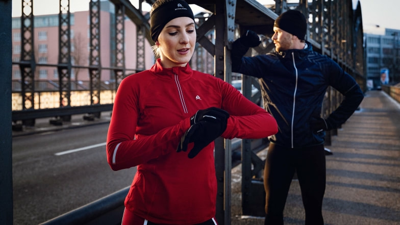 Eine Läuferin checkt auf einer Brücke ihre Sportuhr.