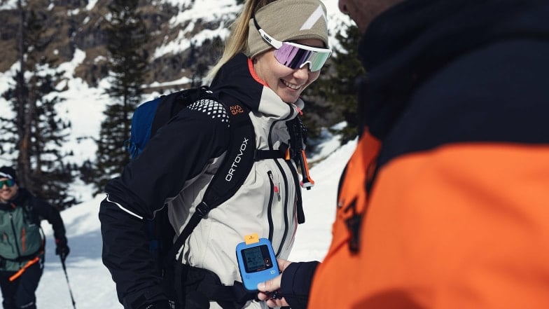 Skitourengeher machen einen LVS-Check in den verschneiten Bergen.