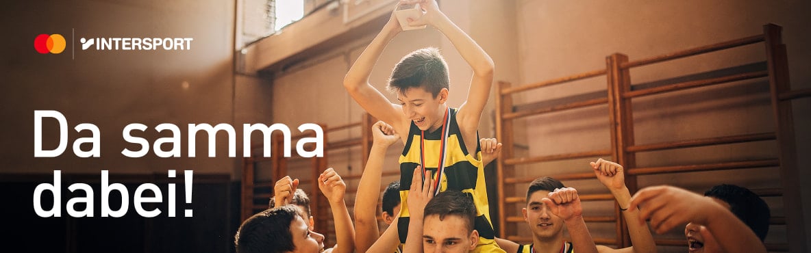 Jubelndes Basketballteam hebt jungen Sieger mit Pokal auf den Schultern in der Sporthalle hoch