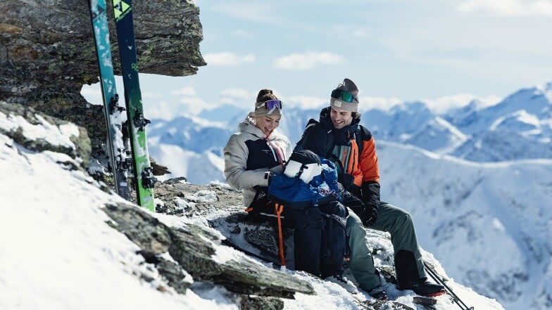 Ein Paar macht eine Pause bei der Skitour in den Bergen.