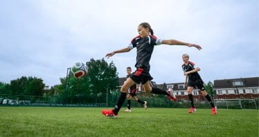 Fußballspielerin schießt einen Ball auf einem Fußballplatz.