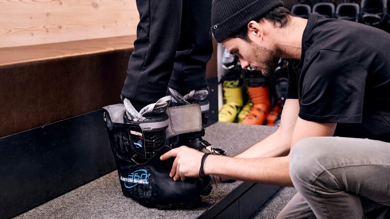 Bootfitting - ein INTERSPORT Mitarbeiter passt gerade Skischuhe an
